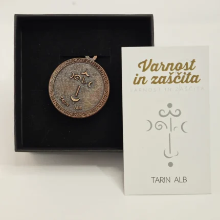 Amulet "Varnost in zaščita" z gravurami lune in napisom "Tarin Alb", skupaj s kartico, ki pojasnjuje simboliko, v elegantni darilni škatlici.